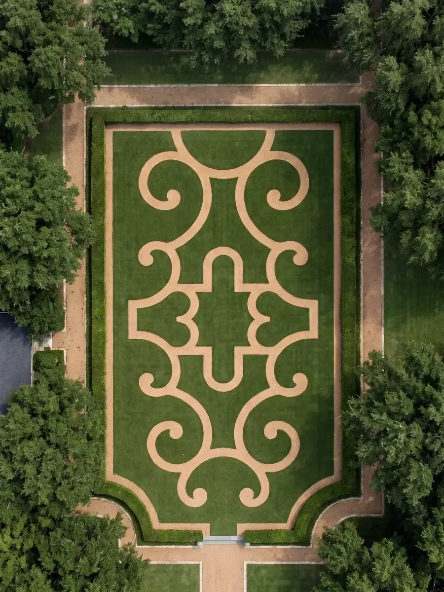 A scroll-pattern parterre of turf and decomposed granite seen from above, framed by oaks